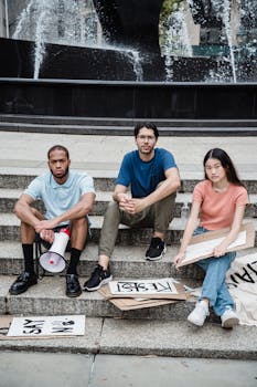 Young activists with protest signs seated on city stairs, symbolizing a peaceful demonstration.